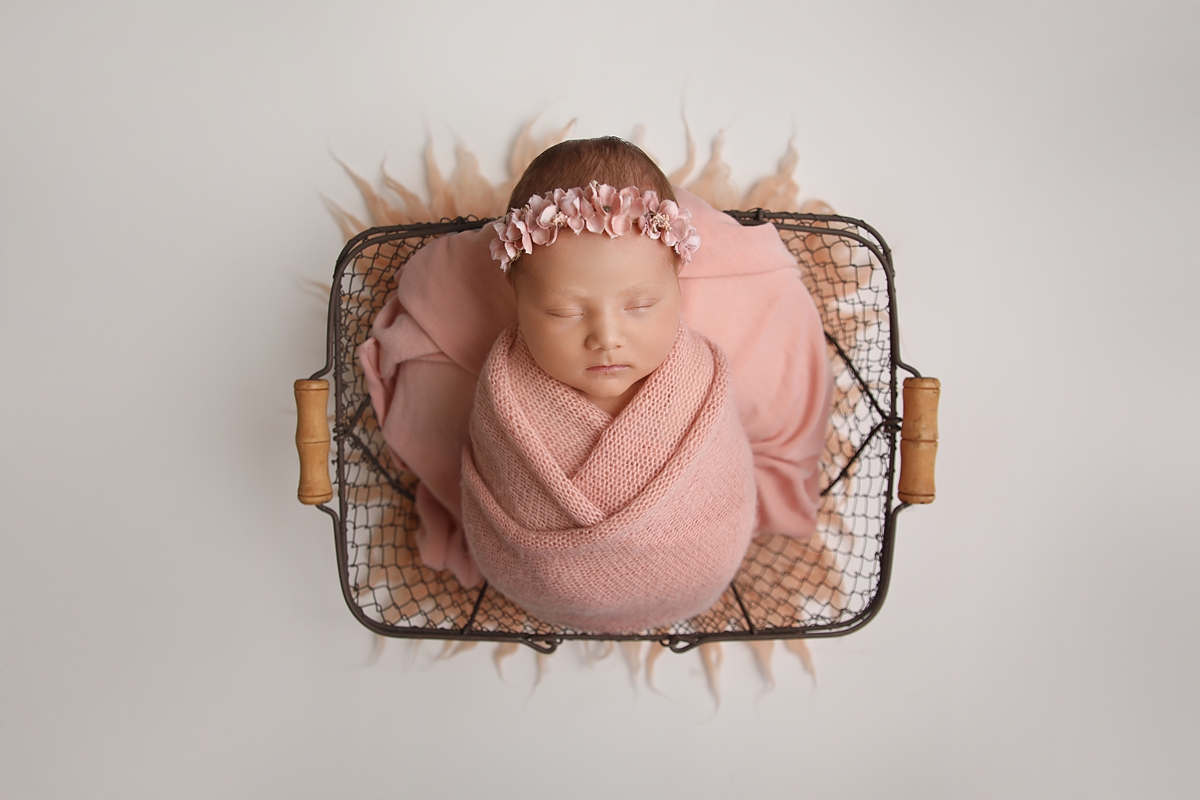 Newborn Girl in a basket with pink wrap