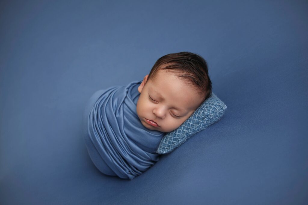 Newborn boy wrapped in blue by a Midway City Newborn Photographer